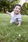 Малыш ползает по траве, улыбается — стоковое фото