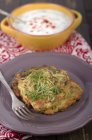 Plate with zucchini fritters with bowl of yogurt dip — Stock Photo