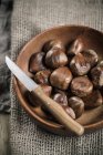 Chestnuts in wooden bowl with knife on sackcloth — Stock Photo