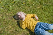 Смеющийся маленький мальчик лежит на лугу — стоковое фото