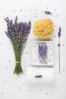 Lavender (Lavendula), white towel, lavender soap on soap basket and natural sponge — Stock Photo