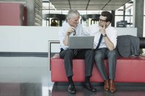 Two caucasian businessmen with laptop in modern office — Stock Photo