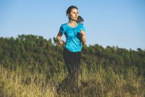 Jovem jogger feminino em movimento na frente da floresta — Fotografia de Stock