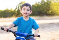 Niño montando en bicicleta en el parque - foto de stock