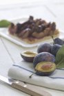 Whole and halved Plums on kitchen towel with knife — Stock Photo
