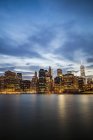 США, Нью-Йорк, вид из Бруклина на освещенный Манхэттен и Ист-Ривер при вечернем свете — стоковое фото