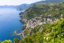 Italia, Liguria, La Spezia, Cinque Terre, Riomaggiore, vista a la costa y pueblo durante el día - foto de stock