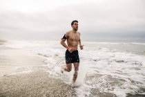 Молодой бесшабашный человек, бегущий в море — стоковое фото