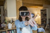 Young woman at home using Virtual Reality goggles — Stock Photo