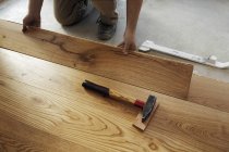 Uomo posa pavimenti in parquet finiti, primo piano — Foto stock