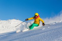 Женщина катается на снежном склоне горы в яркой лыжной одежде, шлеме и Google — стоковое фото
