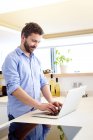 Mann arbeitet in Küche mit Laptop — Stockfoto