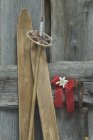 Alte Skier, Skistock, rote Schleife mit Edelweiß (leontopodium alpinum) an Holzwand gelehnt — Stockfoto