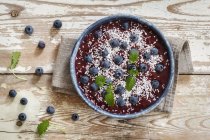 Top view of smoothie bowl with blueberries and coconut flakes on wooden table — Stock Photo