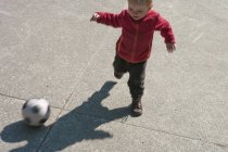 Малыш играет в футбол на открытом воздухе — стоковое фото