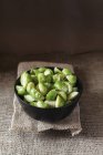 Bowl of blanched brussels sprouts on sackcloth — Stock Photo
