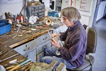 Fabricant d'instruments réparer trompette en atelier — Photo de stock