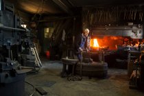 Germany, Bavaria, Josefsthal, senior blacksmith at work in historic blacksmith's shop — Stock Photo