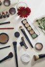 White makeup table with various of cosmetics and flowers, top view — Stock Photo