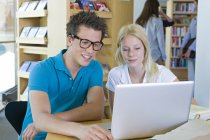 Studenti con computer portatile che imparano in biblioteca — Foto stock