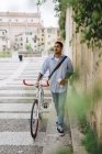 Jeune homme marchant à vélo dans la ville — Photo de stock