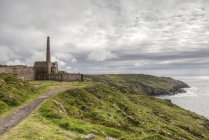 Reino Unido, Inglaterra, Cornwall, mina de estaño en la colina contra el agua - foto de stock