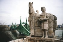 Hungría, Budapest, Escultura de piedra de San Esteban y puente de la Libertad - foto de stock