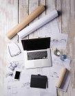 Desk of an architect with laptop and blue prints — Stock Photo