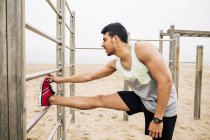Joven estirándose en las barras de la pared en la playa - foto de stock