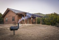 США, Техас, Log home with barbecue smoker in front — стоковое фото