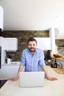 Mann arbeitet in Küche mit Laptop — Stockfoto