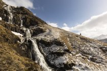 Islanda, Snaefells, escursionista camminando verso l'alto e vista panoramica sulla cascata — Foto stock