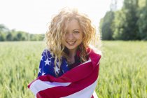 Ritratto di donna sorridente con bandiera americana in natura — Foto stock