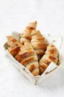 Mini croissants caseros en cesta sobre mantel blanco - foto de stock