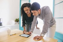 Jeune homme d'affaires et femme utilisant une tablette numérique au bureau — Photo de stock