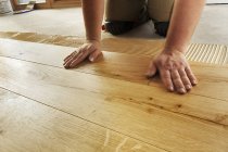 Uomo posa finito pavimenti in parquet di quercia, primo piano — Foto stock