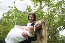 Sposo felice che porta sposa in giardino — Foto stock