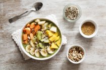 Smoothie bowl with mango, papaya, kiwi, banana, pear, lineseeds, sunflower-seeds and nuts — Stock Photo