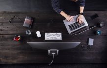 Homme travaillant au bureau avec ordinateur et divers gadgets numériques — Photo de stock