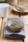 Herbal tea in bowl on wooden surface with fabric — Stock Photo