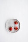 Tre pomodorini rossi in ciotola su fondo bianco — Foto stock