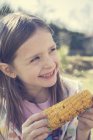 Portrait of little girl with grilled corn cob — Stock Photo