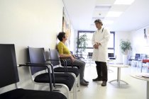 Doctor and patient talking in waiting room — Stock Photo