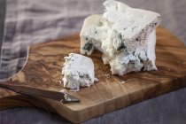Close-up of pieces of Gorgonzola cheese with cheese knife on wooden chopping board — Stock Photo