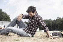 Homme élégant souriant assis sur l'herbe — Photo de stock