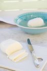 Ciotola di mozzarella, mozzarella affettata e coltello su marmo bianco — Foto stock