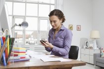 Жінка вдома за столом з комп'ютером і телефоном — стокове фото