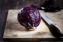 Red cabbage on wooden chopping board with knife — Stock Photo