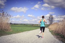 Woman jogging through the rural landscape — Stock Photo
