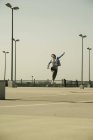 Молодая женщина со скейтбордом прыгает на уровне парковки — стоковое фото